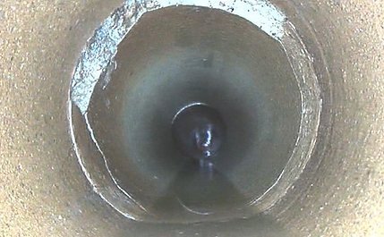 Camera view inside a drain before relining, showing a damaged section of pipe wall